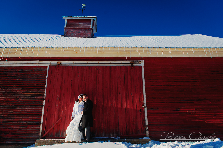 Photo of bride and groom in front of red barn in vermont.
